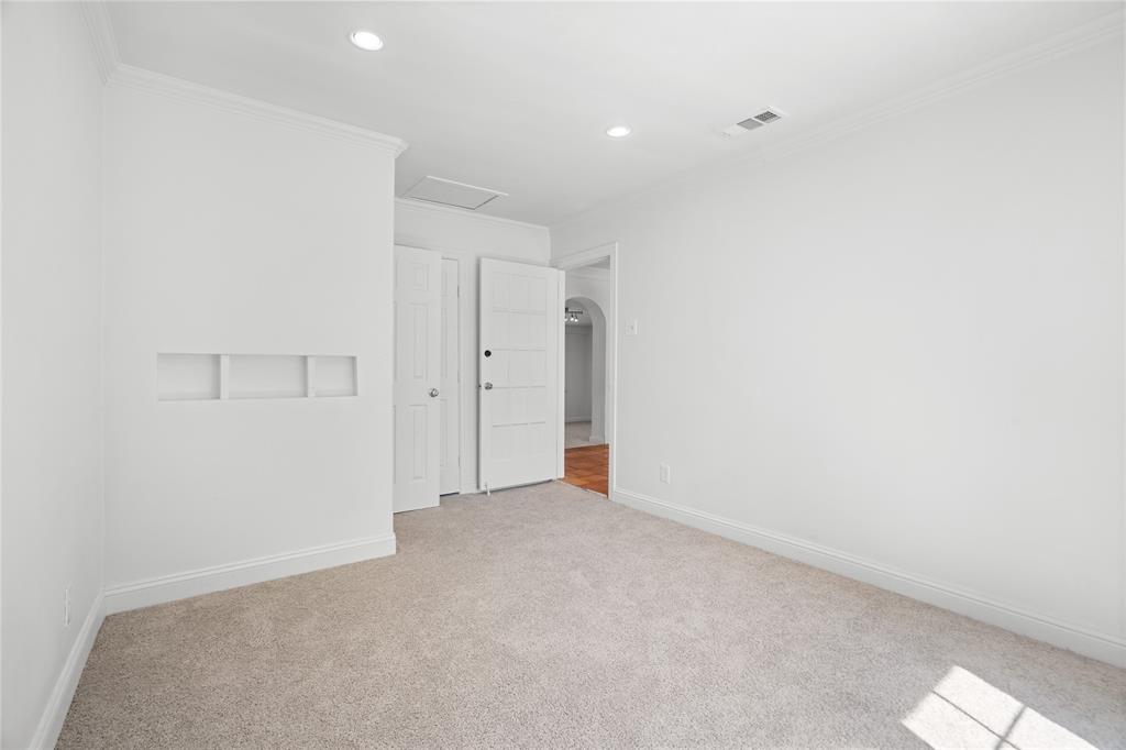 Neutral-toned carpeting, recessed ceiling lighting, crown molding, and a built-in recessed wall niche