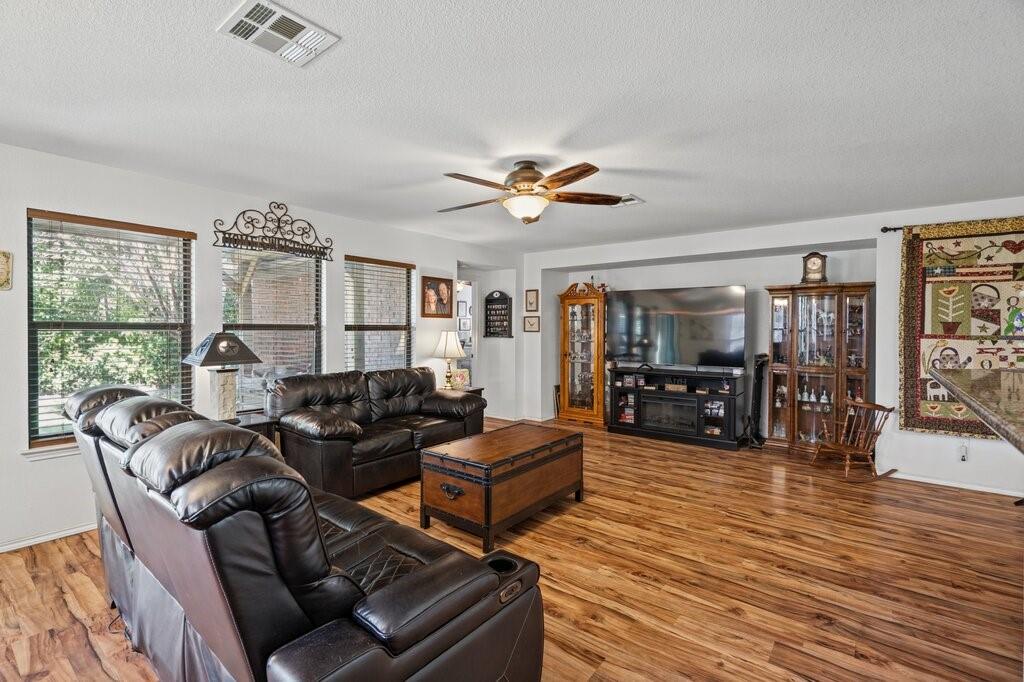 Living area featuring wood-finish flooring, a recessed media alcove, and a multi-blade ceiling fan Living area featuring wood-finish flooring, a recessed media alcove, and a multi-blade ceiling fan