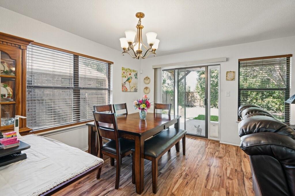 Dining area featuring wood-finish flooring, a five-arm chandelier, built-in cabinetry, and sliding glass doors with exterior access