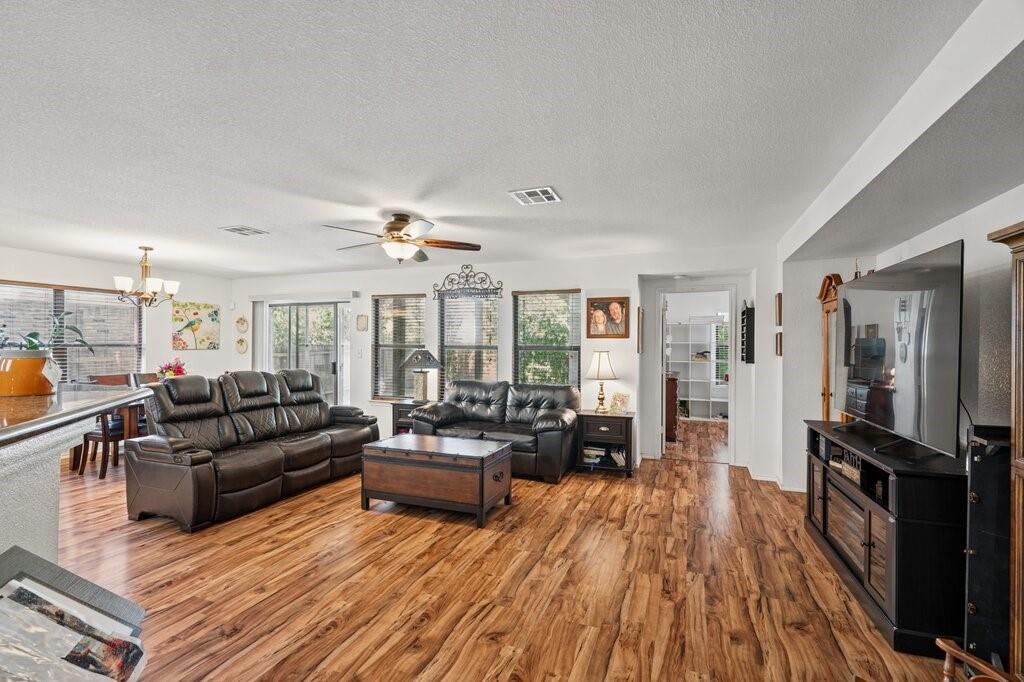 Living area featuring wood-finish flooring, recessed lighting, ceiling fan with light kit, and large windows Living area featuring wood-finish flooring, recessed lighting, ceiling fan with light kit, and large windows