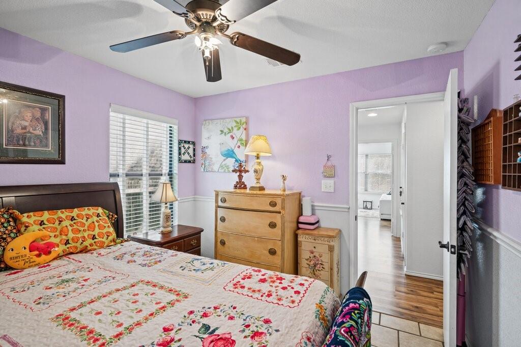 Room featuring white wainscoting, multi-blade ceiling fan, and window with horizontal blinds