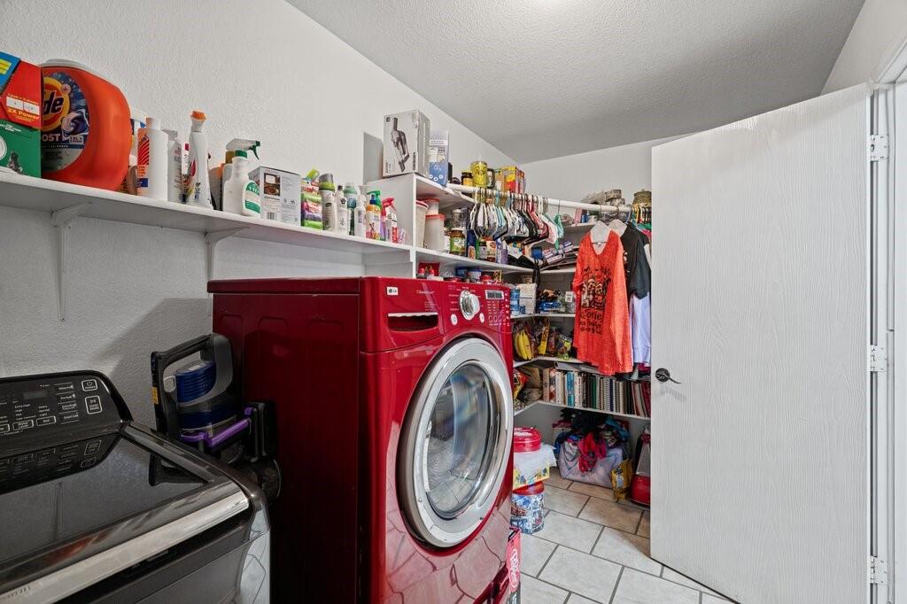 Utility room featuring white tile flooring and wall-mounted shelving units