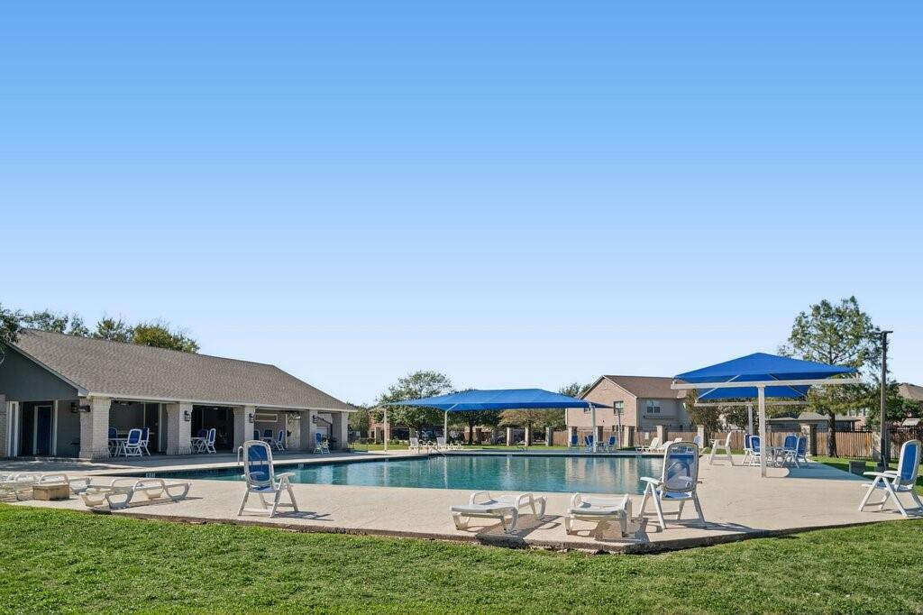 Swimming pool featuring a concrete deck, built-in shade structures, and an attached covered pavilion