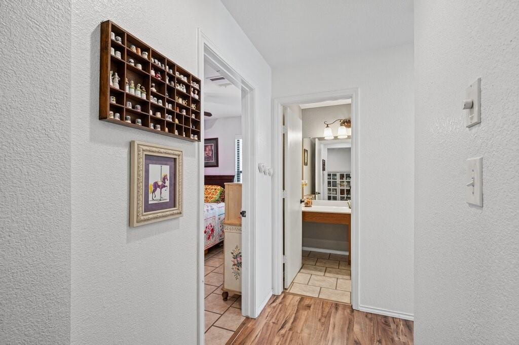 Hallway featuring wood-finish flooring, ceramic tile flooring, and a built-in bathroom vanity with a mirror and multi-bulb light fixture