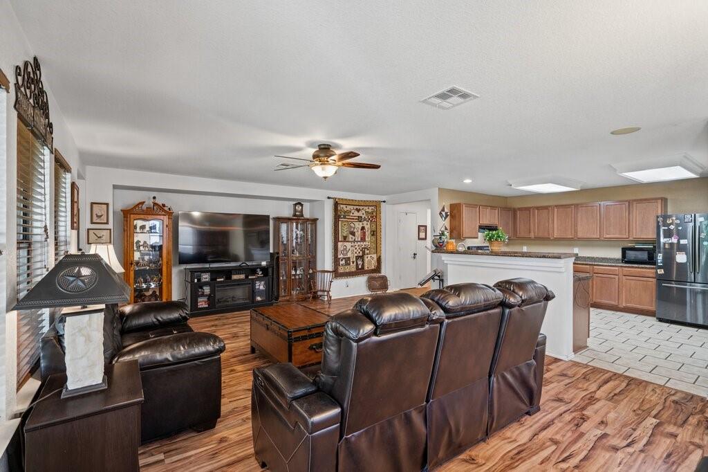Open-concept interior featuring wood-finish flooring, recessed built-in shelving, a ceiling fan, and kitchen cabinetry with a raised breakfast bar Open-concept interior featuring wood-finish flooring, recessed built-in shelving, a ceiling fan, and kitchen cabinetry with a raised breakfast bar