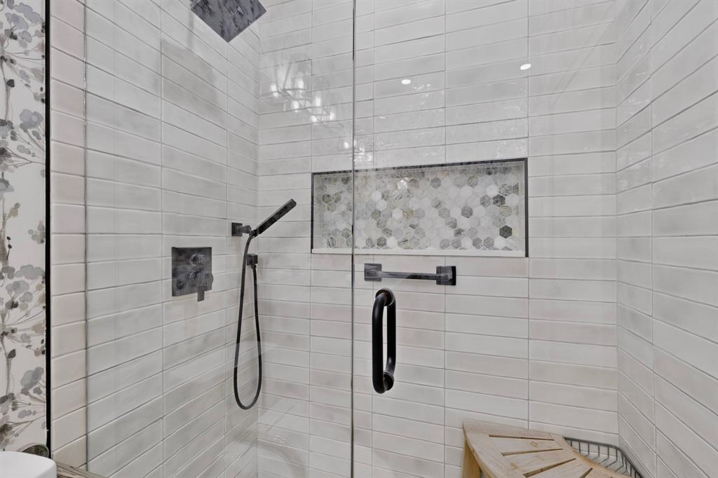 The walk-in shower features a rainfall showerhead, hand-held shower wand, and grab bars for stability.