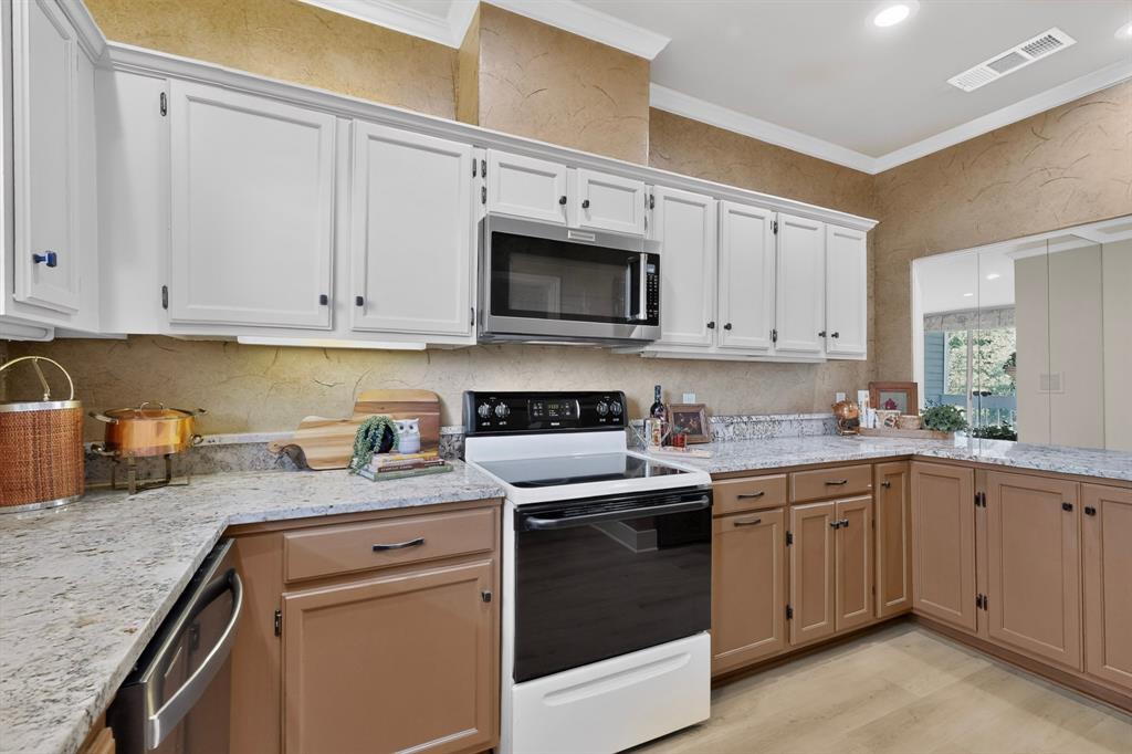 Kitchen featuring two-tone cabinetry, speckled stone-finish countertops, stainless steel microwave, and wood-finish flooring.