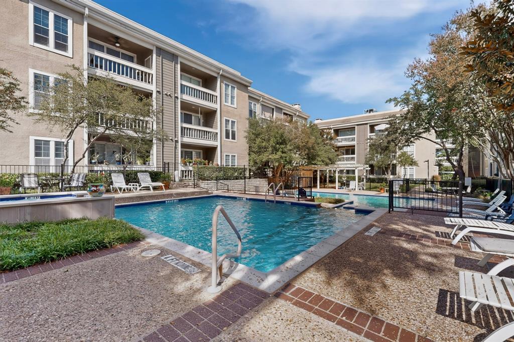 Gather for a dip at the complex swimming pool with integrated spa, surrounded by a sunbathing deck, mature landscaping, and security fence.
