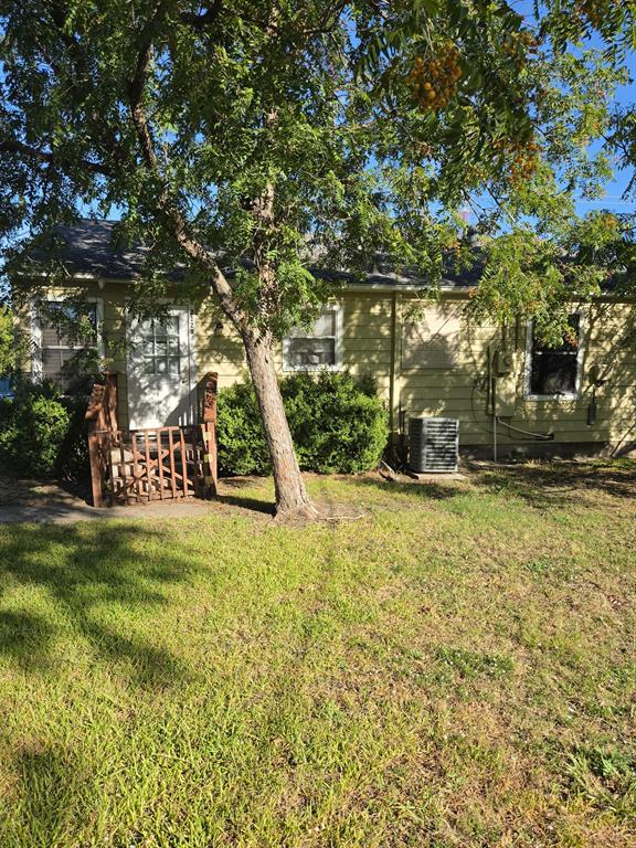 Single-story residence featuring lap siding, multiple windows, a rear wood-railing entry, and mature perimeter landscaping Single-story residence featuring lap siding, multiple windows, a rear wood-railing entry, and mature perimeter landscaping