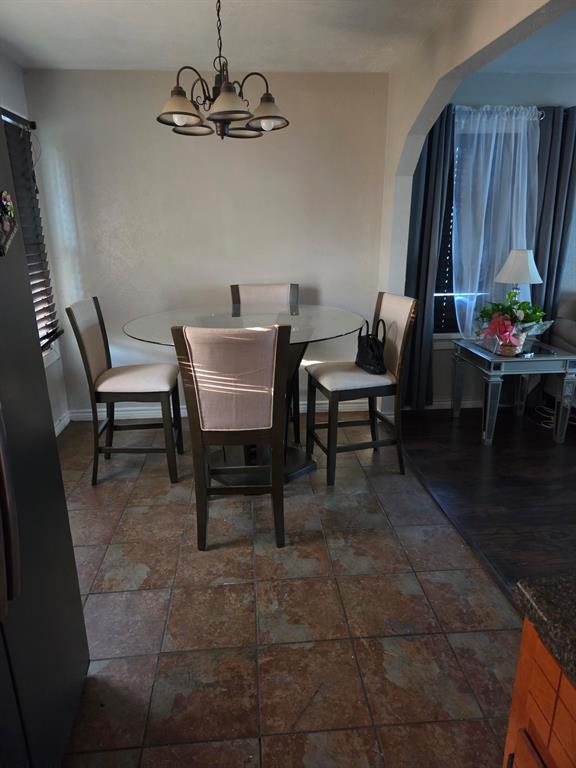Textured tile flooring, arched wall detailing, and a multi-light metal chandelier Textured tile flooring, arched wall detailing, and a multi-light metal chandelier