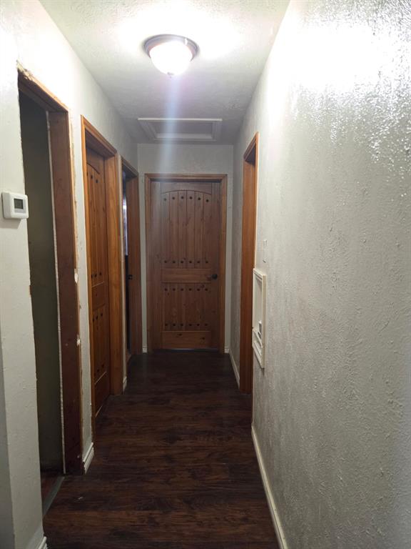 Hallway featuring wood-finish flooring, solid wood doors with arched decorative paneling, and a flush-mount light fixture