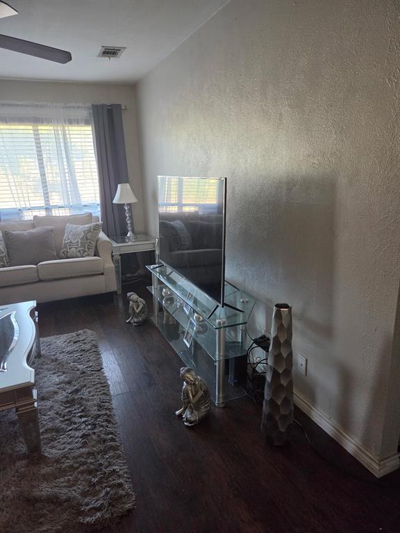 Room featuring dark wood-finish flooring, a neutral textured wall finish, and a ceiling-mounted fan