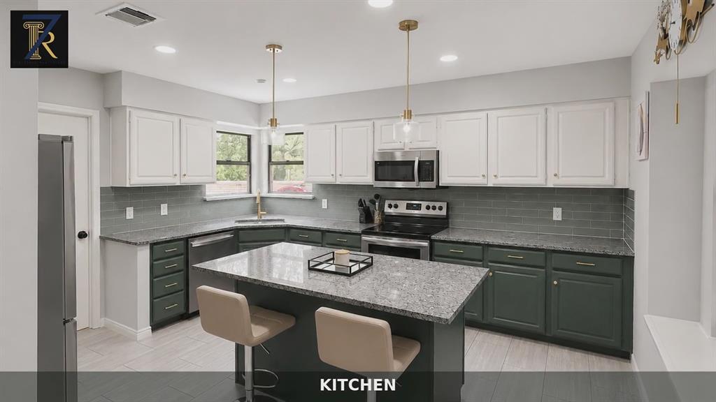 Kitchen featuring two-tone cabinetry, stone countertops, gray subway tile backsplash, stainless steel appliances, and a central island with pendant lighting