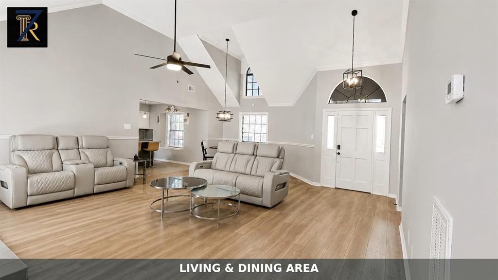 Vaulted ceilings, wood-finish flooring, arch-top windows, integrated ceiling fan, and pendant lighting