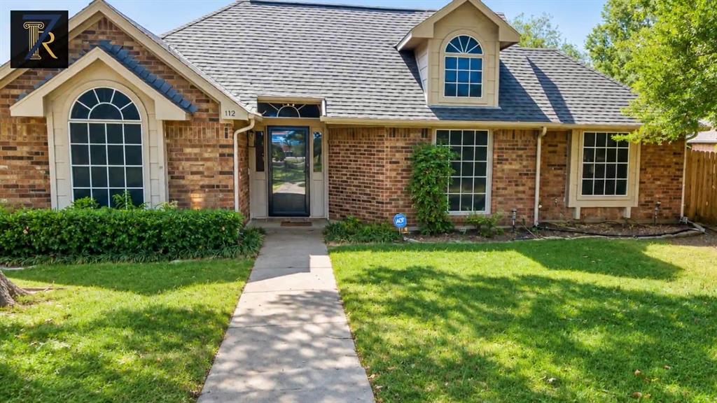 Multi-gabled brick exterior featuring arched windows, a multi-pitched shingled roof, a front-facing dormer, and a concrete walkway Multi-gabled brick exterior featuring arched windows, a multi-pitched shingled roof, a front-facing dormer, and a concrete walkway
