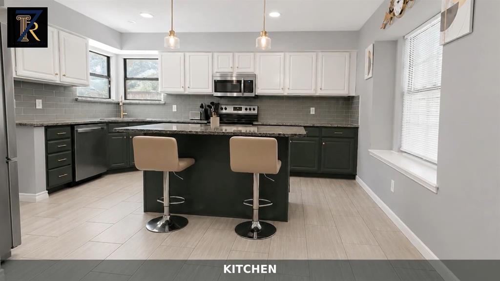 Kitchen featuring dual-tone cabinetry, stone-finish countertops, subway tile backsplash, a center island, and stainless-steel appliances