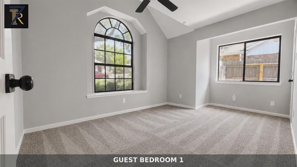 Vaulted ceiling with an arched window, neutral wall coloring, carpeted flooring, and a ceiling fan