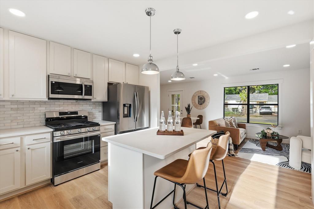 Kitchen featuring shaker-style cabinetry, a central island with a quartz countertop, stainless steel appliances, subway tile backsplash, and recessed lighting