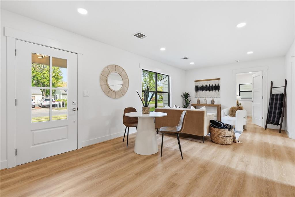 Open-concept area featuring light wood-finish flooring, recessed lighting, white four-panel door with glass inserts, and black-framed windows Open-concept area featuring light wood-finish flooring, recessed lighting, white four-panel door with glass inserts, and black-framed windows
