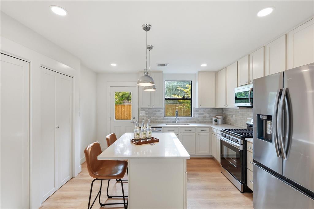 Kitchen featuring white shaker-style cabinetry, quartz countertops, a central island, recessed lighting, and stainless steel appliances