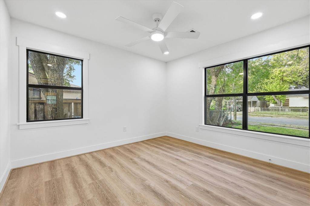 Neutral interior featuring wood-finish flooring, recessed lighting, a white ceiling fan, and large windows with black frames