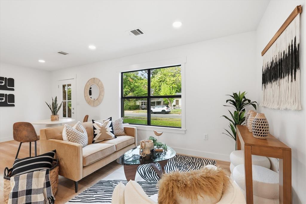 Bright living area featuring wood-finish flooring, recessed lighting, and a large window with black frame detailing Bright living area featuring wood-finish flooring, recessed lighting, and a large window with black frame detailing