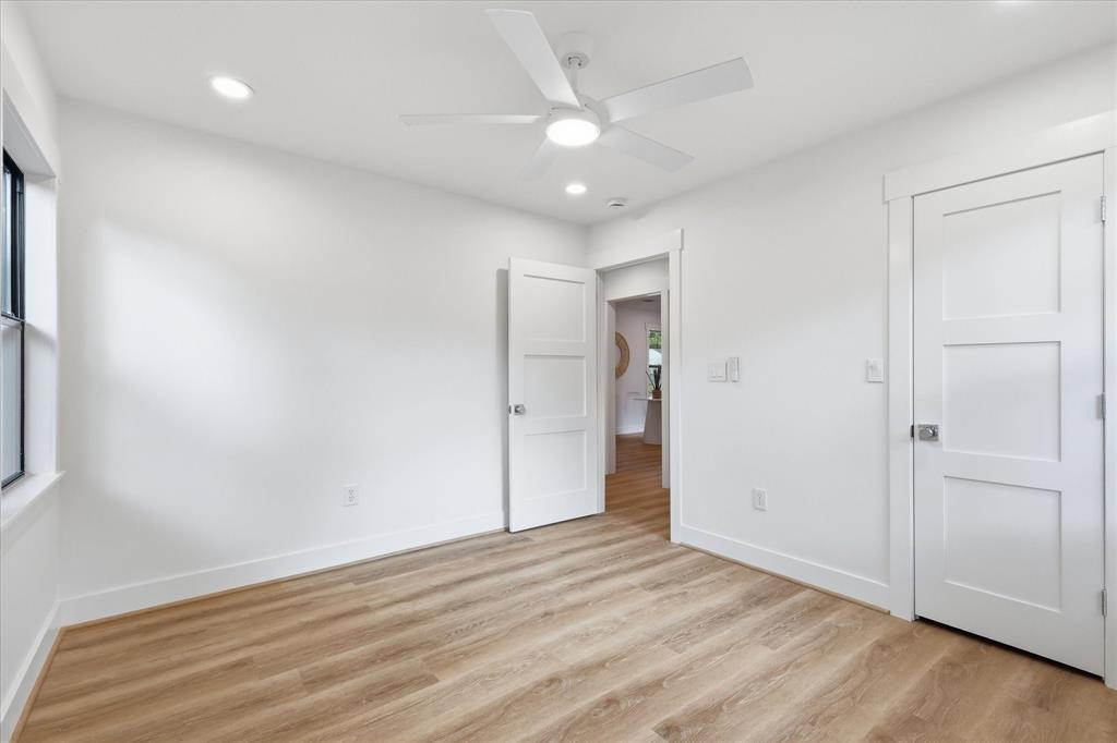 Neutral interior featuring wood-finish flooring, white three-panel doors, recessed lighting, and a modern ceiling fan with an integrated light fixture