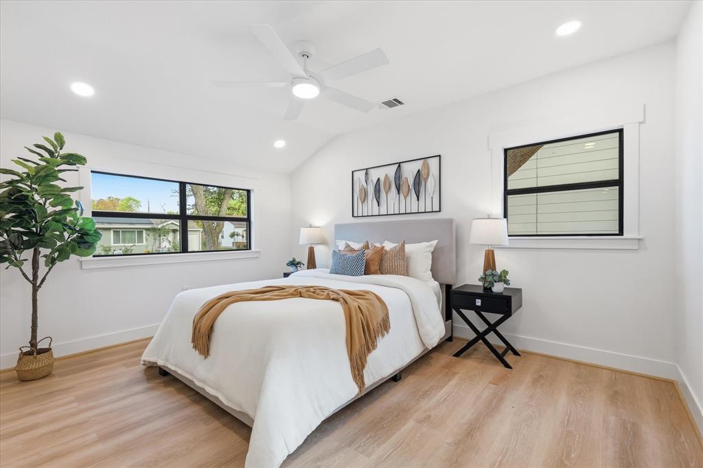 Bedroom featuring wood-finish flooring, vaulted ceilings, recessed lighting, a white ceiling fan, and windows with black frames