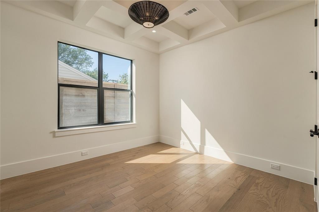 Coffered ceiling with a geometric pendant light fixture, wood-finish flooring, and large window with matte black framing