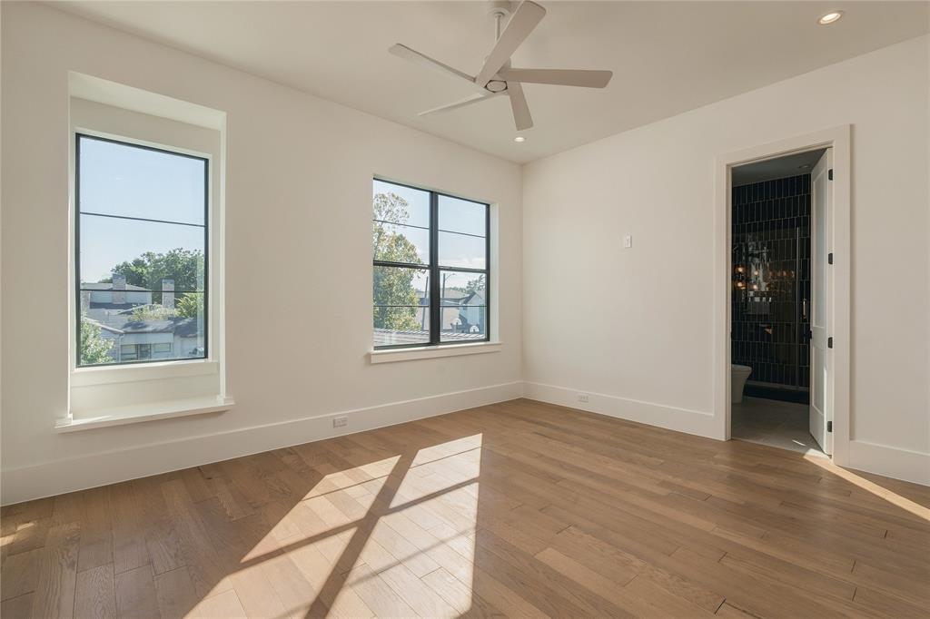 Interior room featuring wood-finish flooring, multi-pane windows with black frames, and a modern ceiling fan