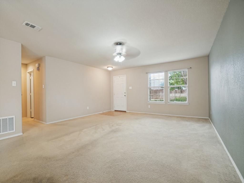 Spacious main living area with ceiling fan and windows overlooking the front yard.