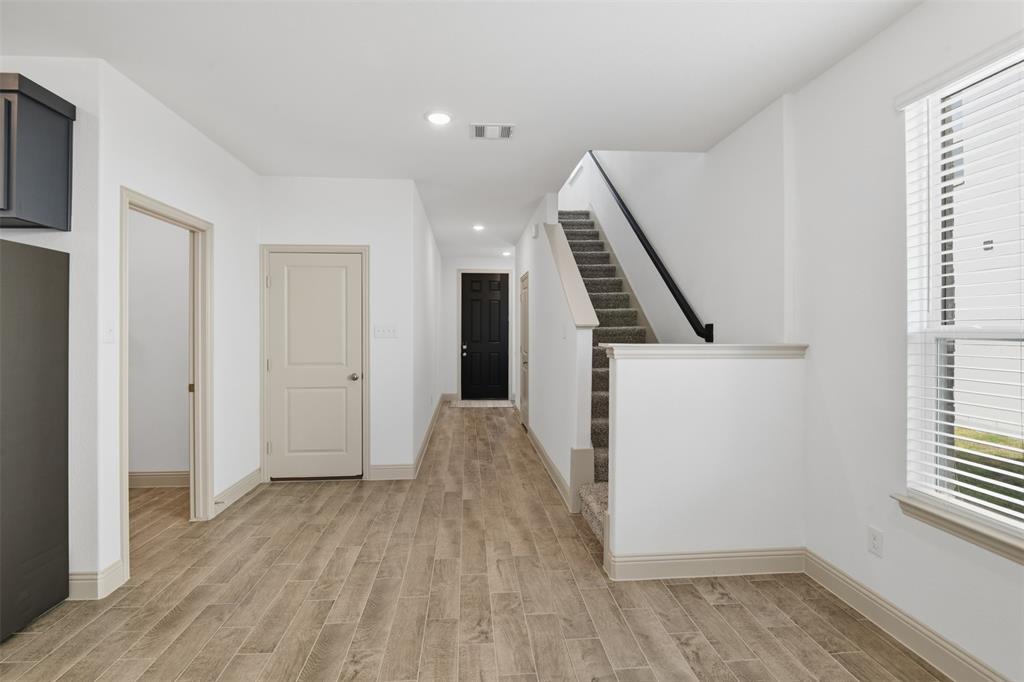 Interior featuring wood-finish tile flooring, recessed lighting, staircase with carpeted treads and a matte black handrail, and windows with horizontal blinds