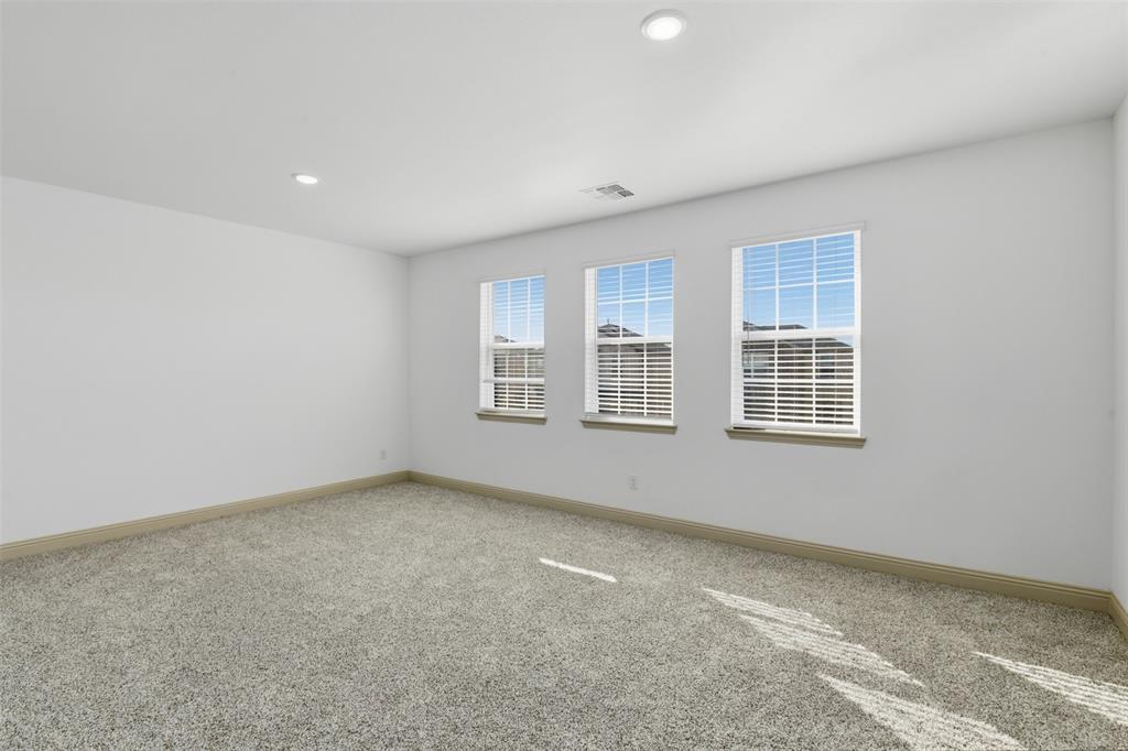 Neutral-toned carpeted flooring, recessed lighting, and three double-hung windows