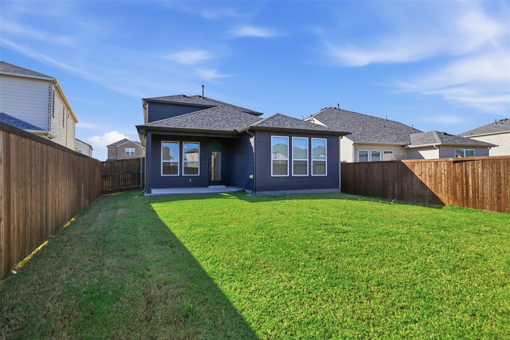 Rear exterior featuring dark-toned horizontal siding, a concrete patio, a private fenced yard, and multiple windows with white trim
