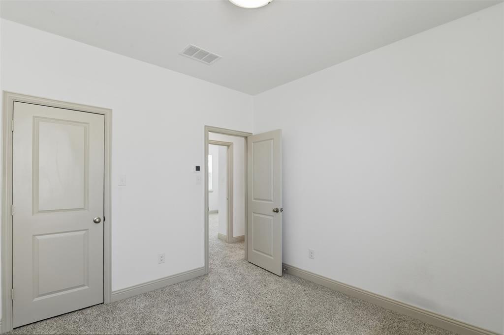 Neutral-toned interior space featuring wall-to-wall carpeting, white walls, and two-panel interior doors with brushed nickel hardware