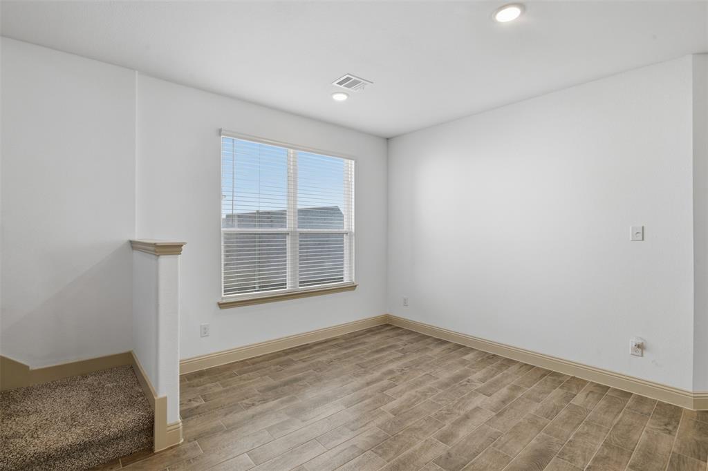 Interior space featuring wood-finish flooring, a double-pane window with integrated blinds, and recessed lighting