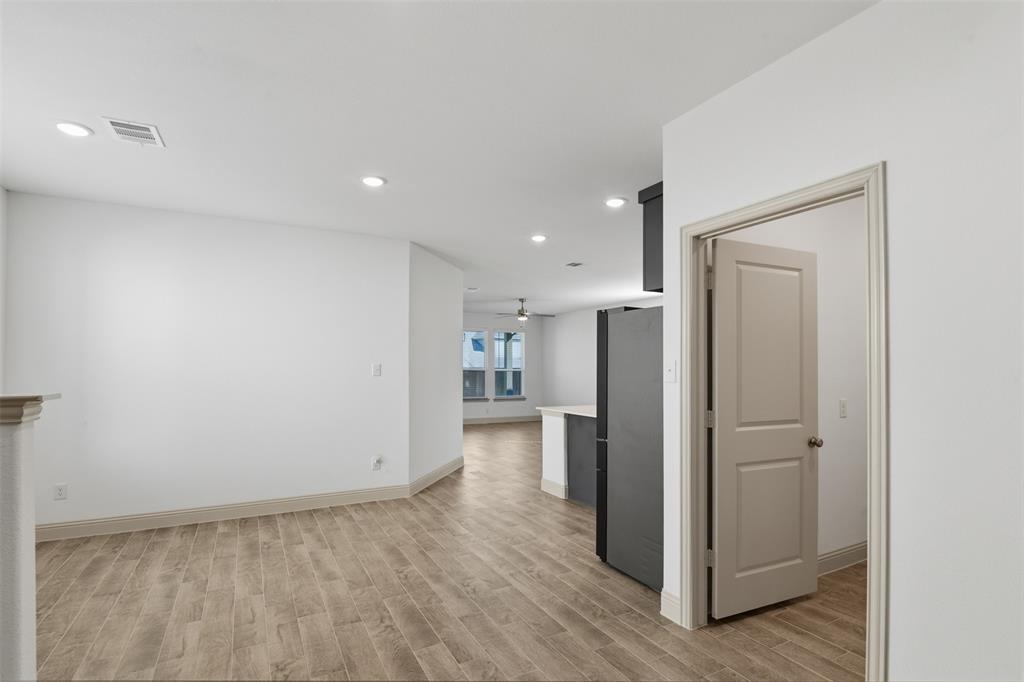 Open floor plan featuring wood-finish flooring, recessed lighting, and a neutral color palette with a shaker-style interior door