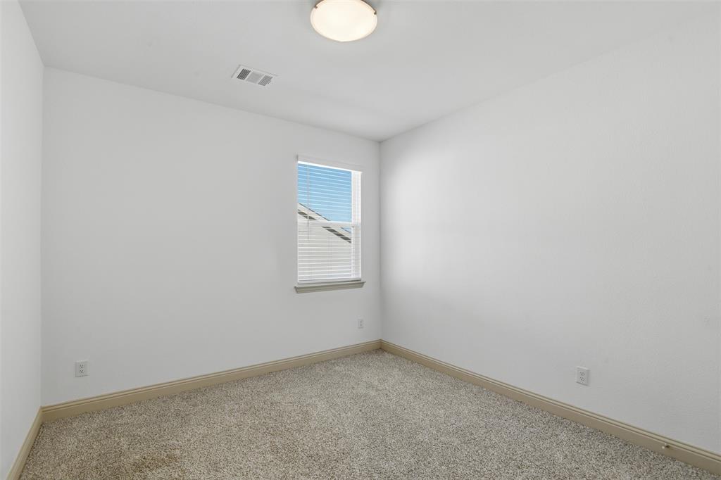 Neutral-toned wall-to-wall carpeting, single-pane window with horizontal blinds, and flush-mount ceiling light fixture