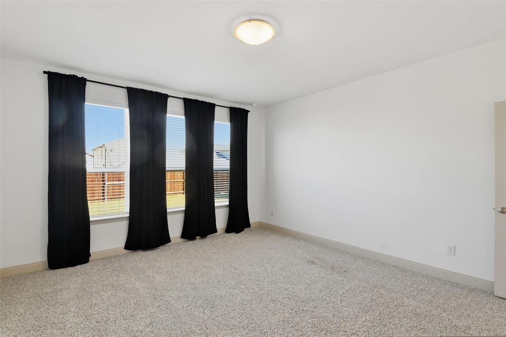 Neutral-toned carpeted flooring, expansive windows with horizontal blinds, and a centrally mounted flush-mount ceiling light fixture