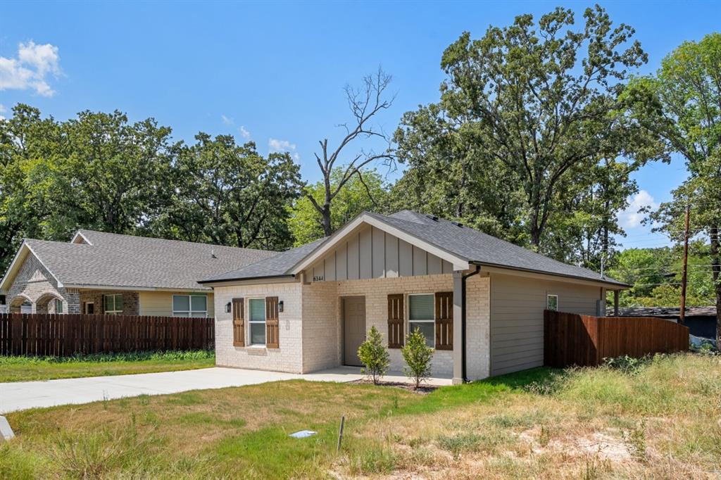 Single-story residence featuring a brick and vertical siding facade, gable roofline, decorative window shutters, and a concrete driveway Single-story residence featuring a brick and vertical siding facade, gable roofline, decorative window shutters, and a concrete driveway