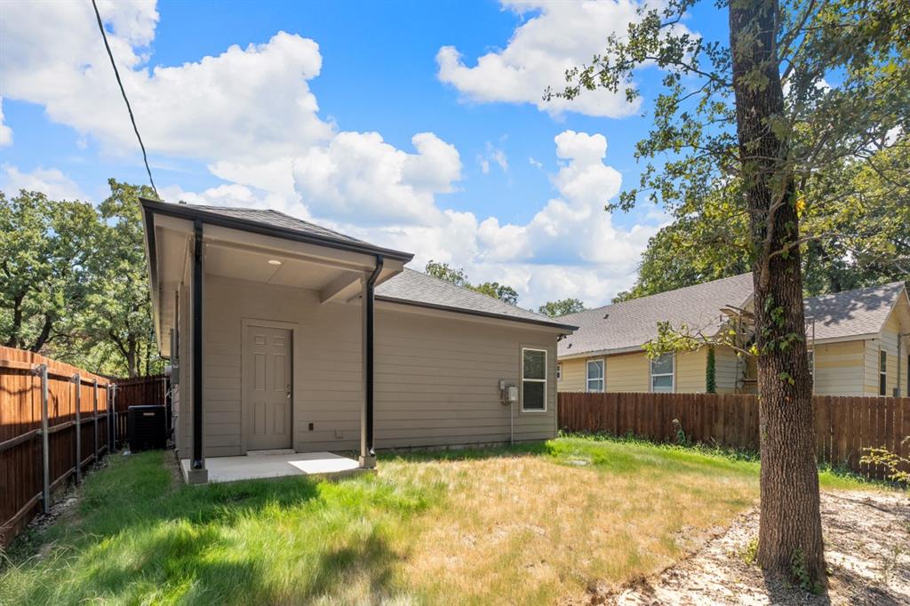Rear exterior featuring a covered concrete patio, horizontal siding, and a wooden perimeter fence