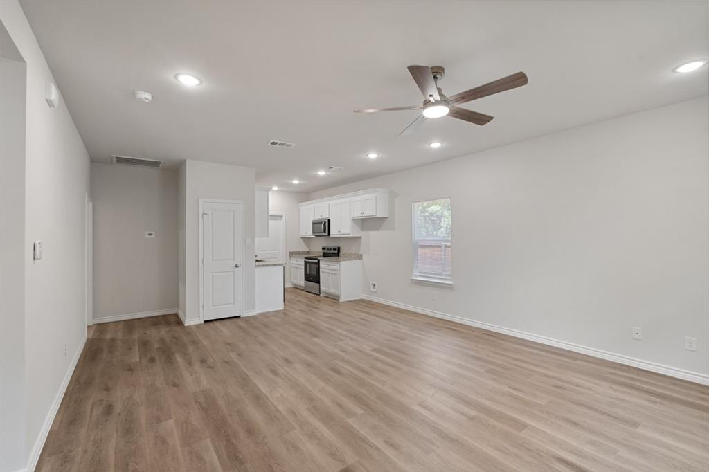 Open-concept interior featuring wood-finish flooring, recessed lighting, a ceiling fan, and white cabinetry paired with stainless steel appliances