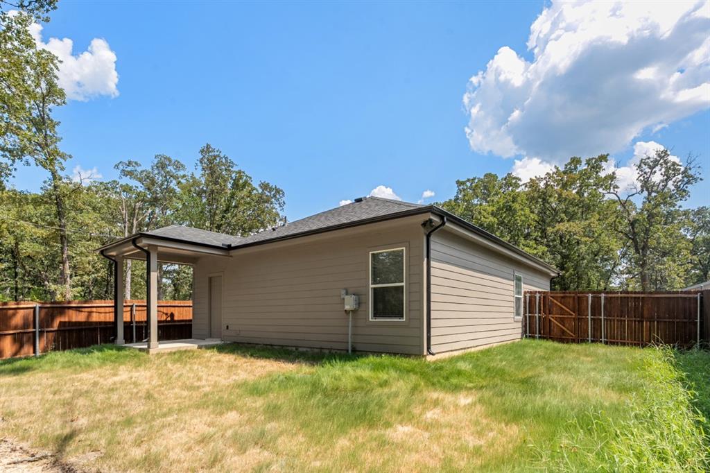 Rear exterior featuring horizontal lap siding, a covered porch, and a wood privacy fence
