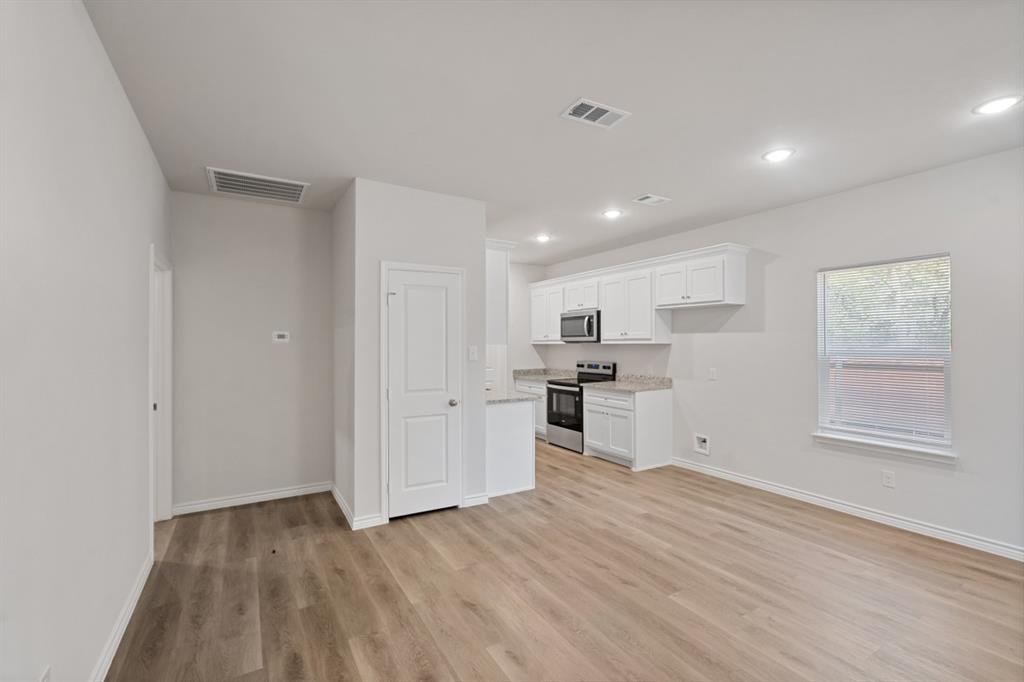 Kitchen featuring white cabinetry, stone-finish countertops, stainless steel appliances, and wood-finish flooring