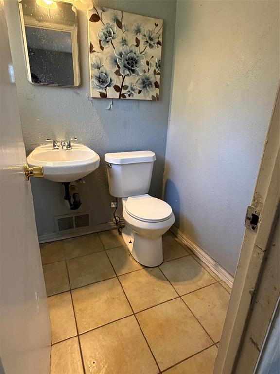 Wall-mounted sink with dual-handle faucet and ceramic tile flooring