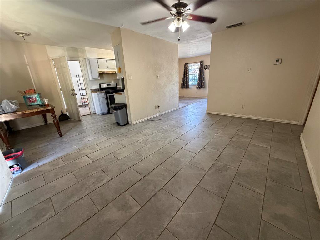 Large format ceramic tile flooring and a ceiling-mounted light fixture with a multi-blade fan