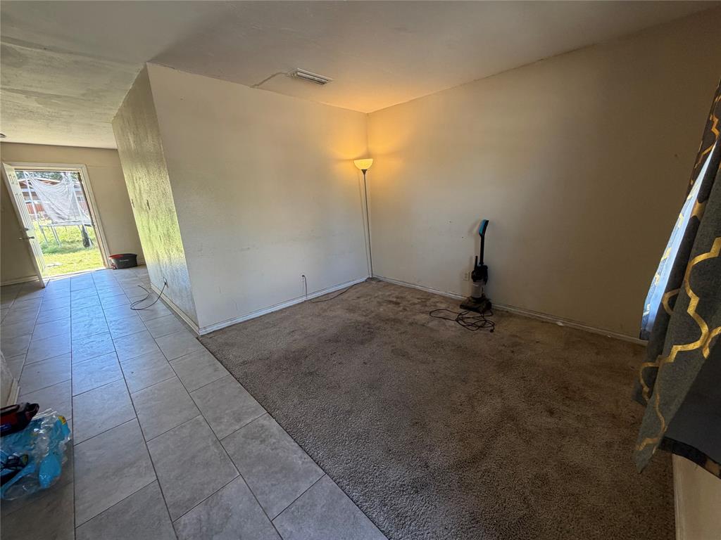 Neutral-toned carpeted flooring with tile flooring accents and a glass-paneled entry door