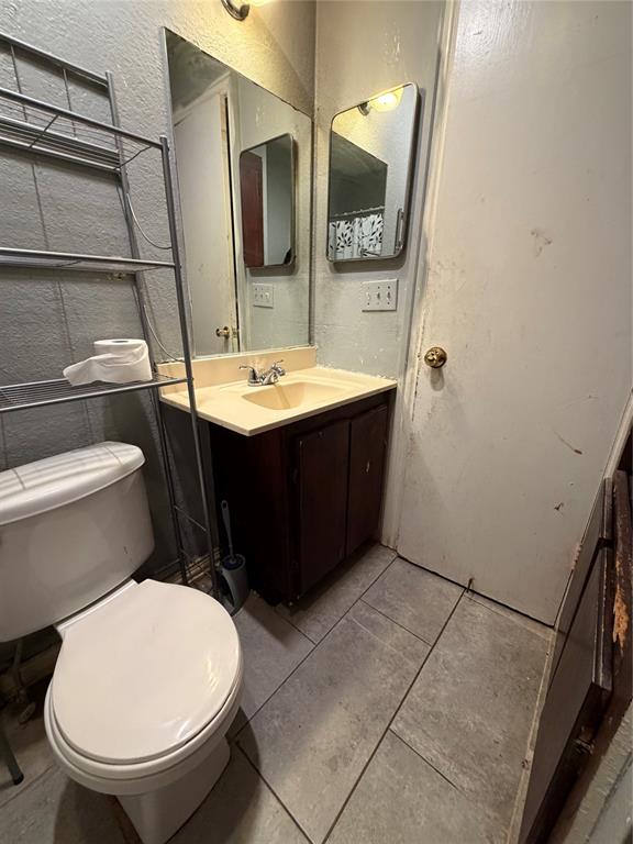 Bathroom featuring tile flooring, a dark-finish wood vanity with a molded countertop, a wall-mounted rectangular mirror, and an integrated medicine cabinet