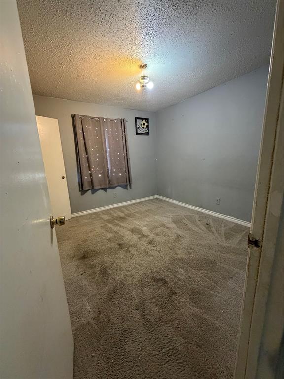 Interior room featuring neutral wall paint, wall-to-wall carpeting, and a central ceiling-mounted light fixture