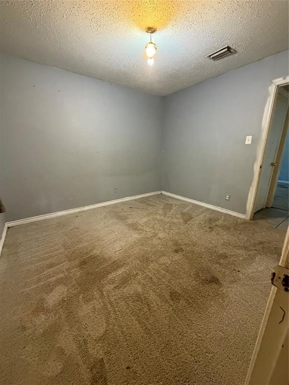 Room featuring carpeted flooring, neutral painted walls, and a center-mounted pendant light fixture